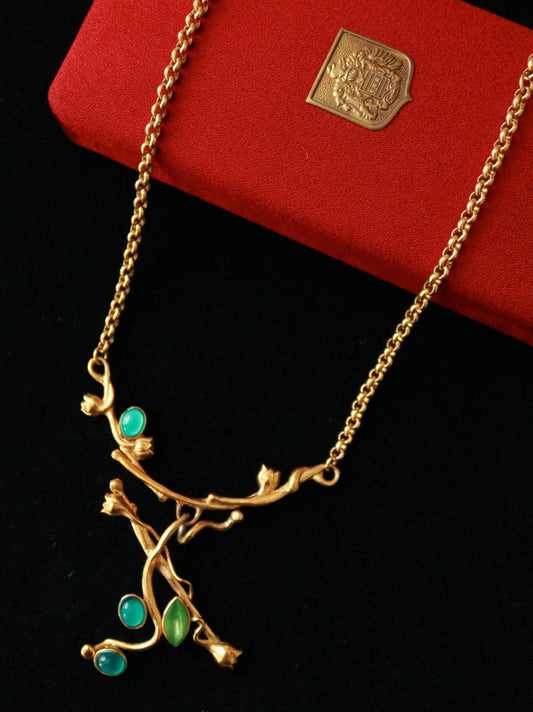 Close-up of a vintage MICRIS necklace featuring an asymmetrical branch design with green cabochon accents.