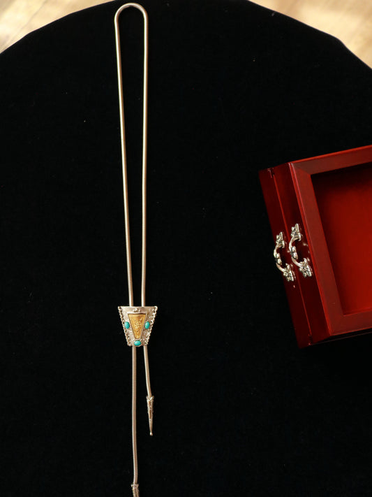 Vintage adjustable bolo-style lariat necklace with turquoise-tone cabochons and ornate triangular slider displayed on black velvet.