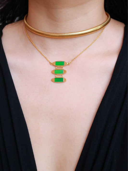 Close-up of a vintage hallmarked vermeil pendant featuring geometric gold-tone forms and green jade.