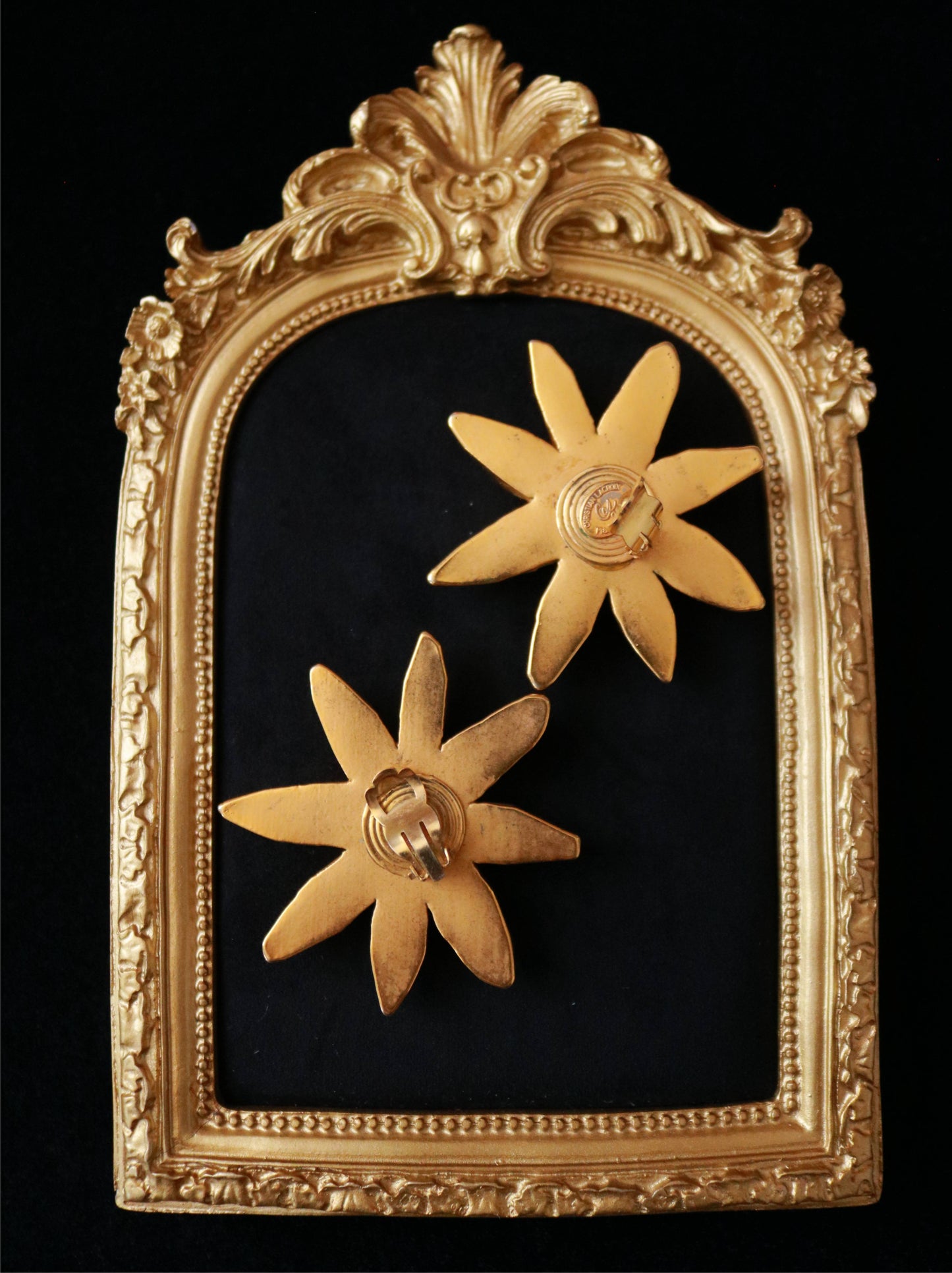 Close-up of signed Christian Lacroix vintage starburst clip-on earrings featuring sculptural faceted gold-tone petals.