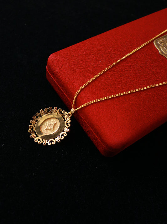 Close-up of vintage FIX gold plated medallion pendant featuring a central faux pearl and red crystal details.