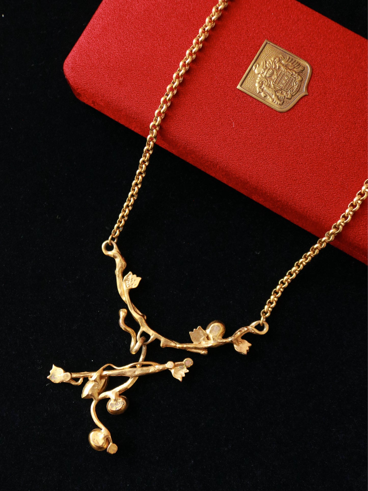 Close-up of a vintage MICRIS necklace featuring an asymmetrical branch design with green cabochon accents.