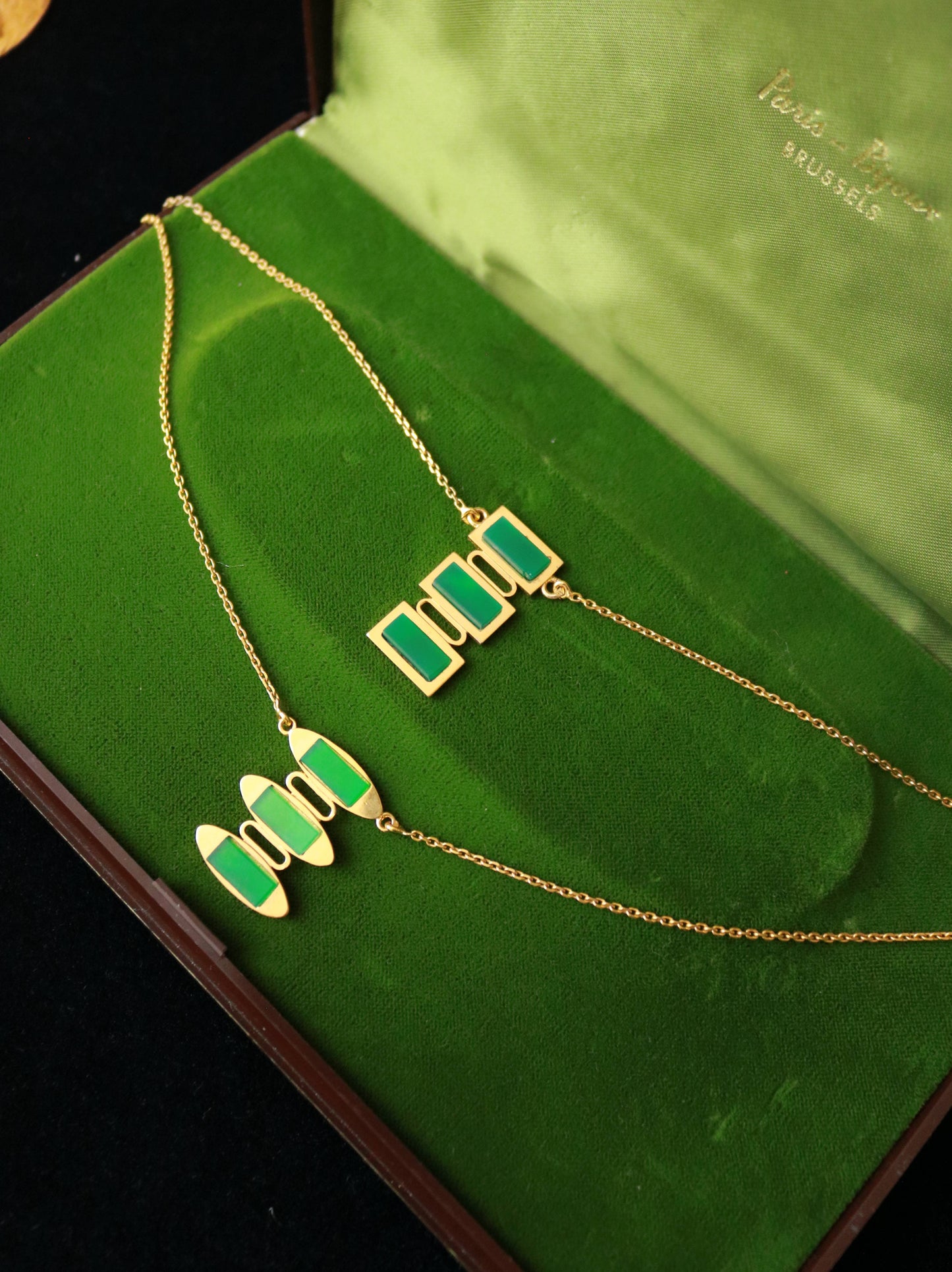 Vintage vermeil geometric pendant necklace set with green jade on a green velvet jewelry box.