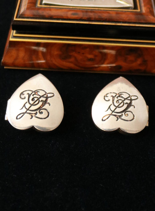 vintage silver color Signed Chantal Thomass heart-shaped box clip-on earrings with an ornate monogram displayed on black velvet.