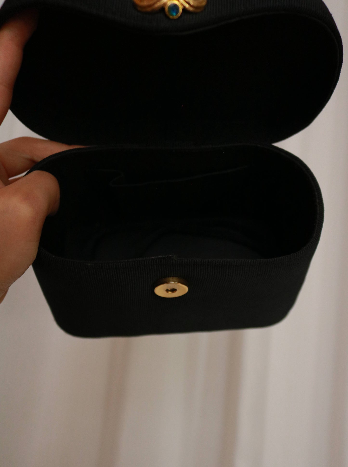 Close-up of the Edouard Rambaud handbag featuring an ornate gold-tone handle and multicoloured jewel-like decoration.