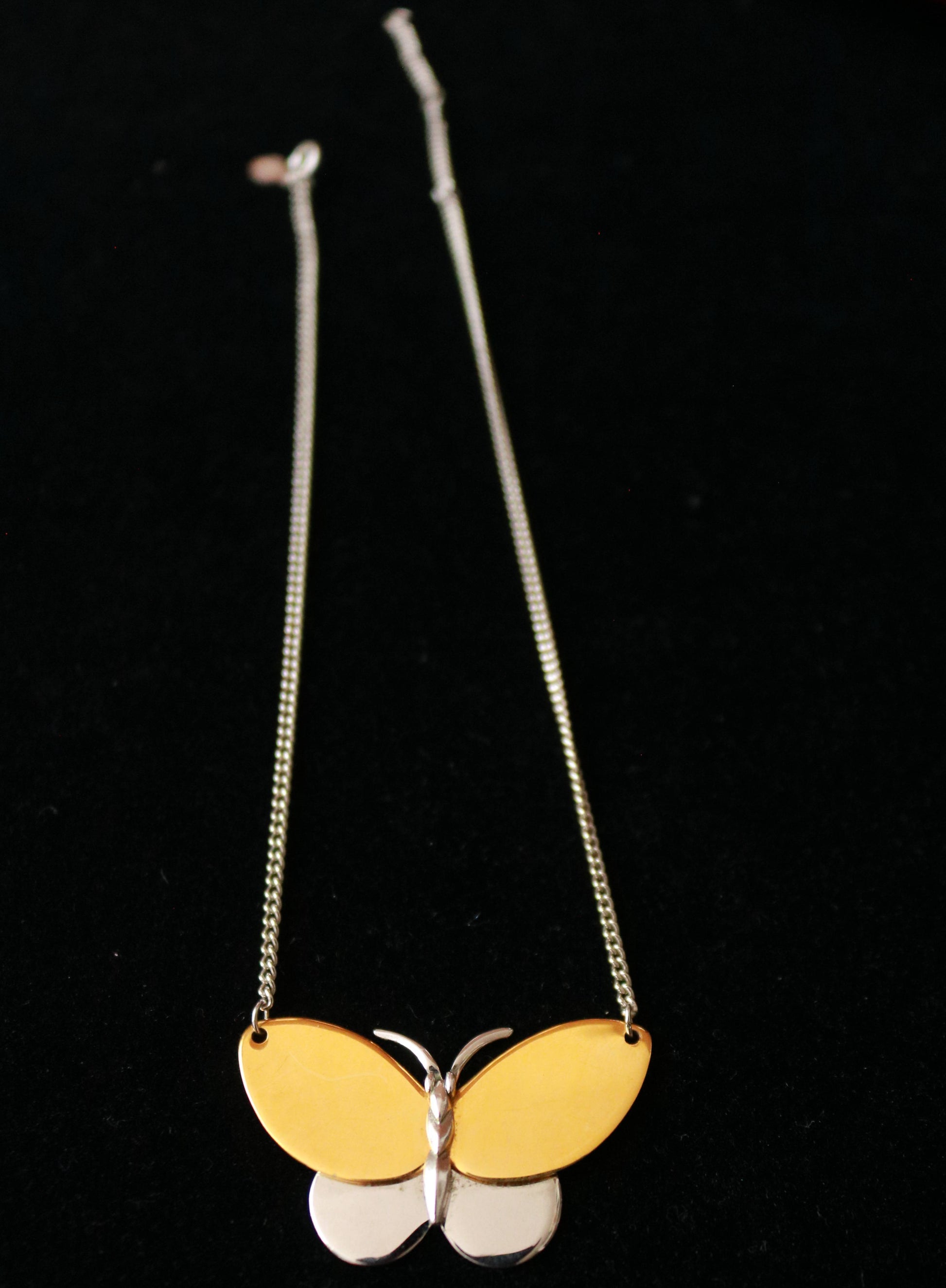 Close-up of a signed AVON vintage butterfly pendant featuring a sculptural two-tone gold and silver-tone design.