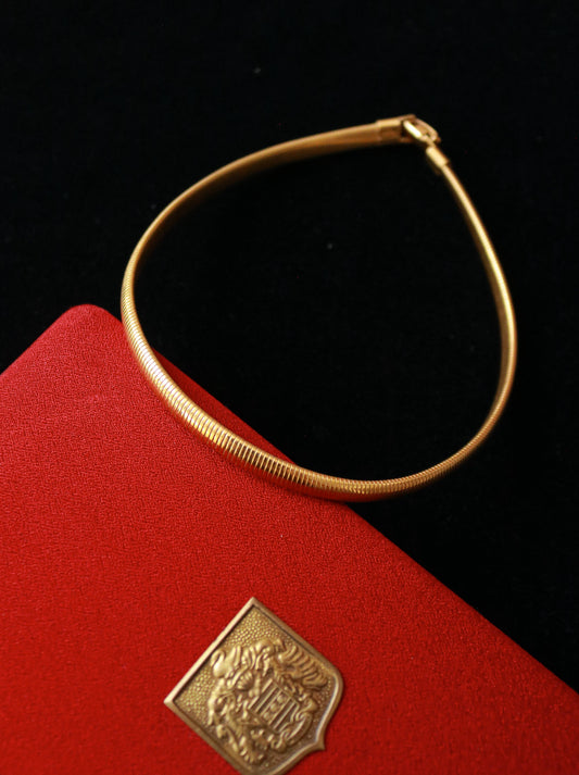 Close-up of vintage gold tone snake chain choker necklace featuring a flexible tubular design.