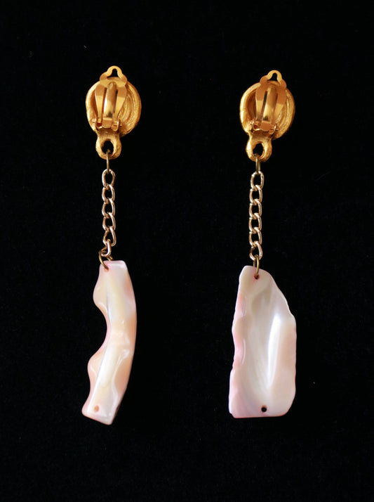 Close-up of vintage long clip-on earrings featuring sculptural gold-tone spiral clips and natural shell drops.