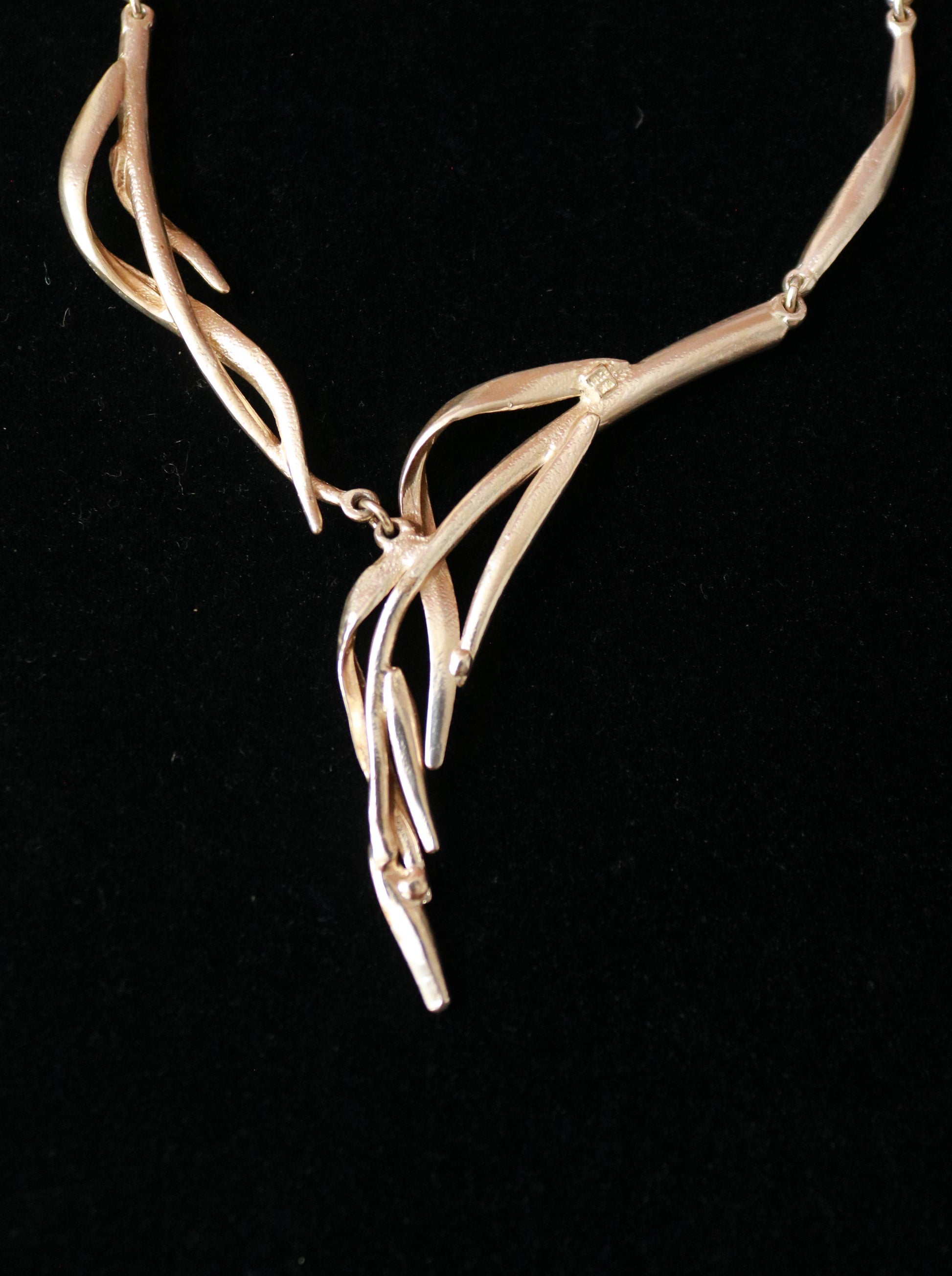 Close-up of a signed Dolce Vita necklace featuring elegant curved and intertwined sculptural metal elements.