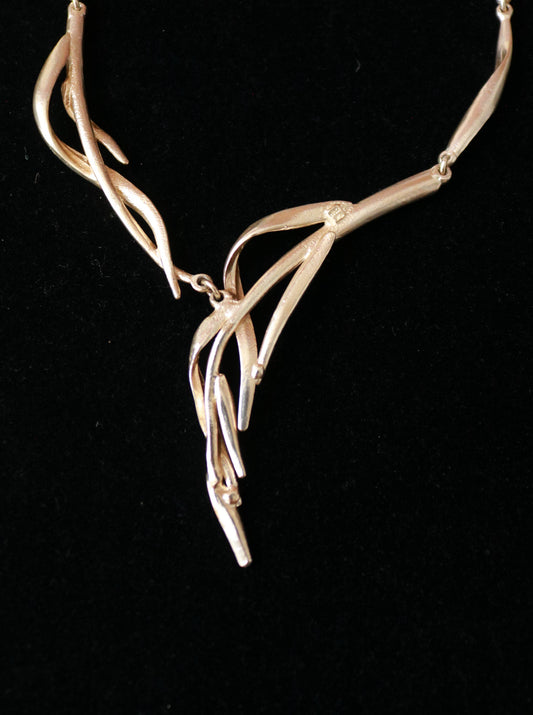Close-up of a signed Dolce Vita necklace featuring elegant curved and intertwined sculptural metal elements.