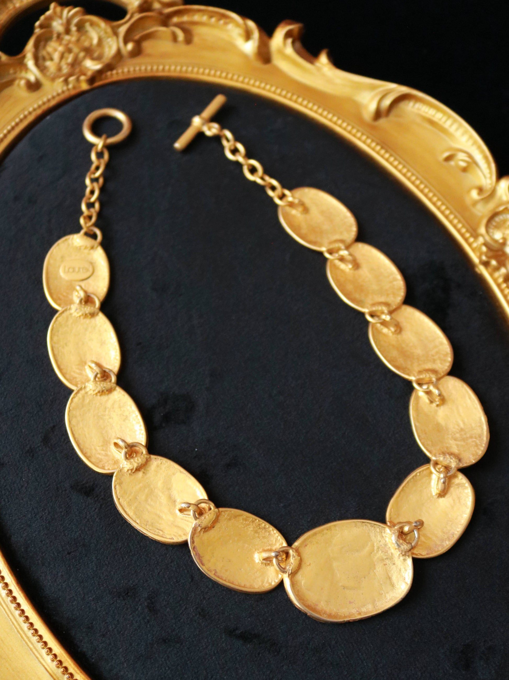Close-up of signed Laurès vintage necklace featuring sculptural gold-tone oval medallions with classical relief motifs.