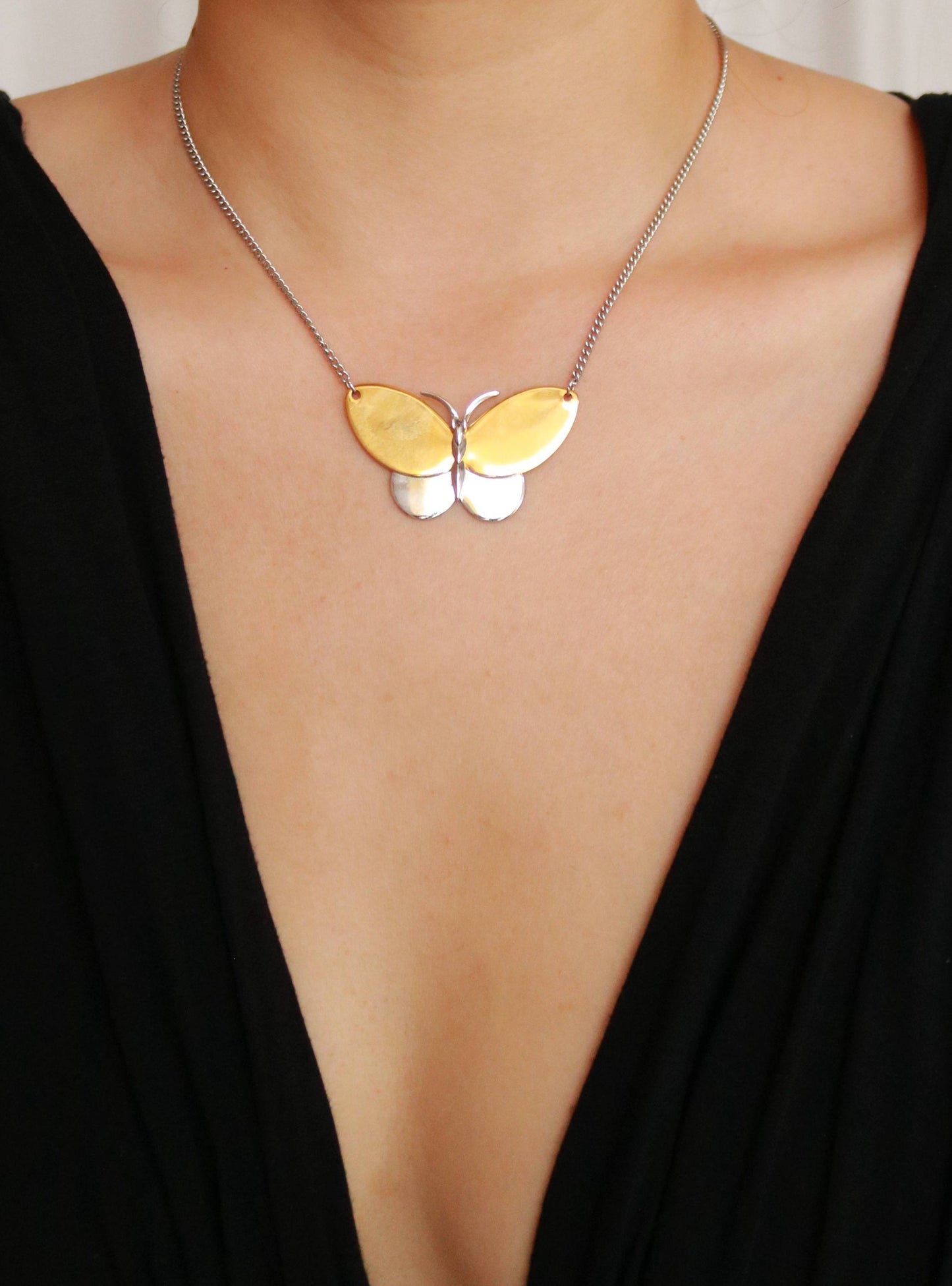 Vintage AVON gold-plated two-tone butterfly pendant necklace worn around the neck.
