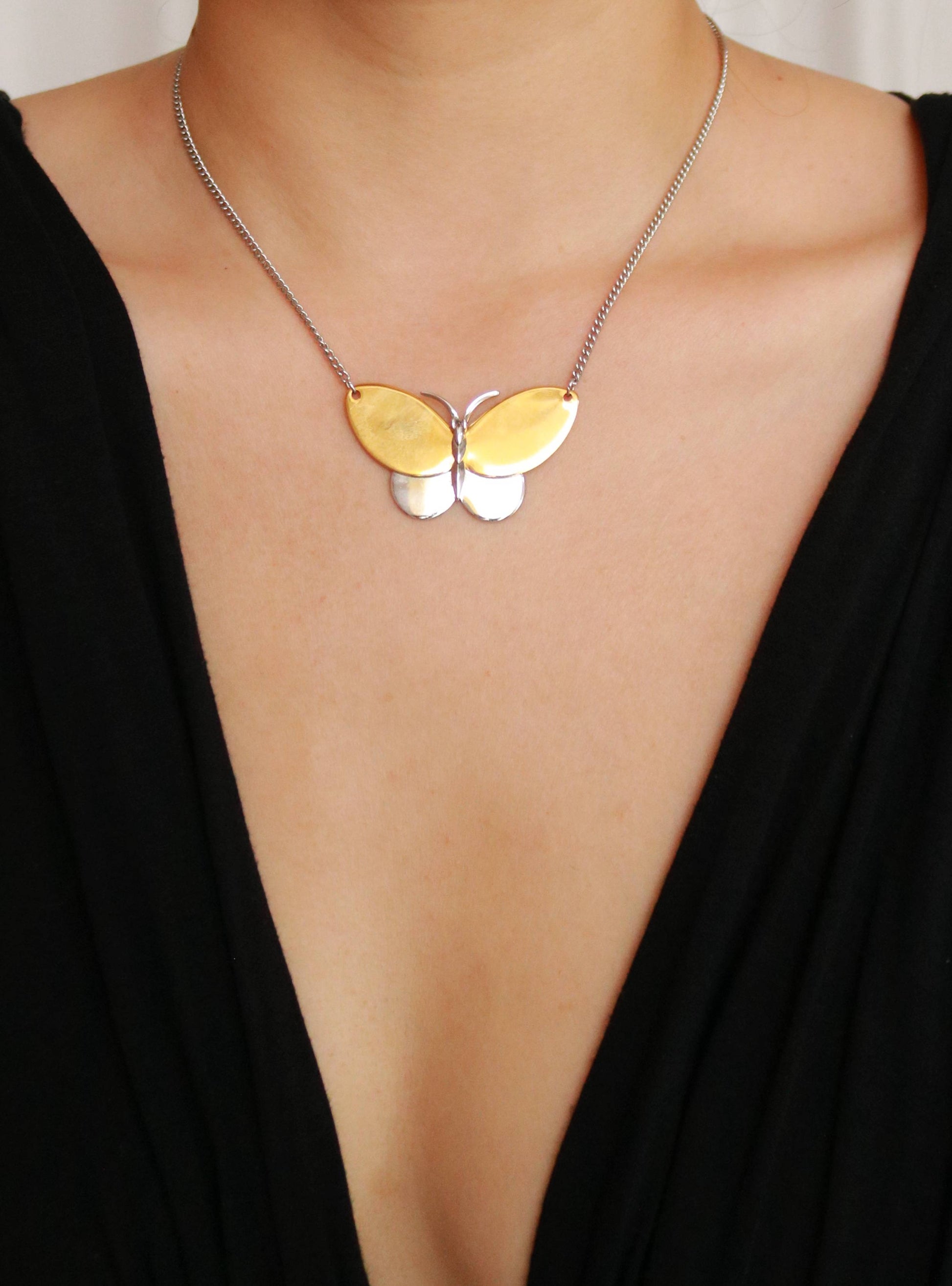 Vintage AVON gold-plated two-tone butterfly pendant necklace worn around the neck.